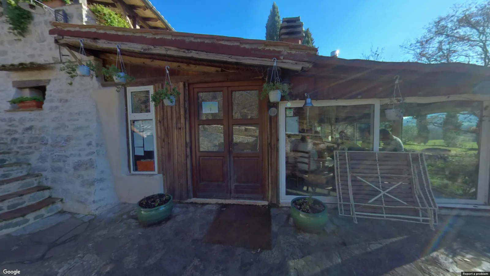 The wooden entrance doors of the Arc at ASHA, with hanging plants and a stone wall